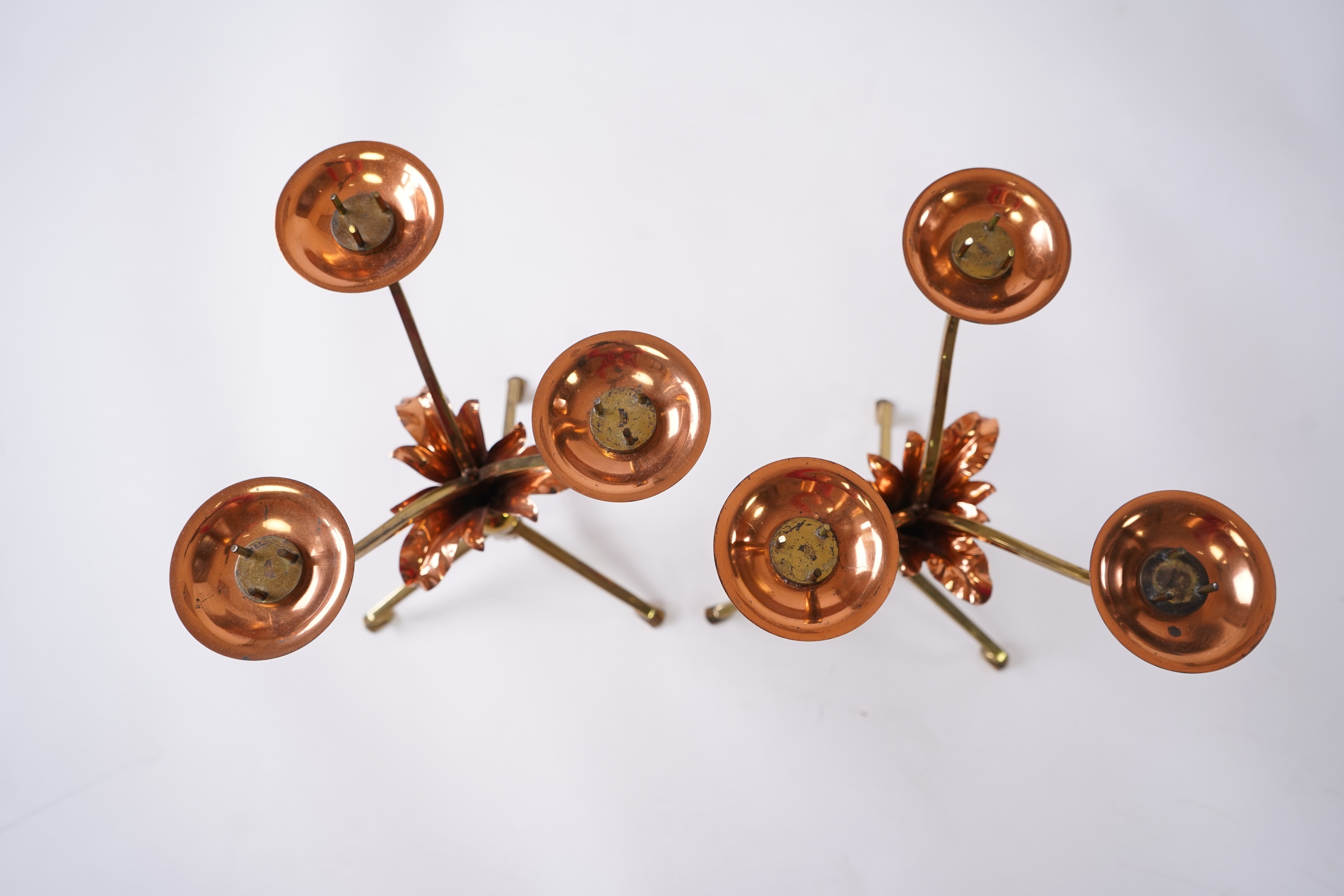 W.A.S. Benson & Co.: A pair of Arts and Crafts gilt brass and copper three branch candelabra